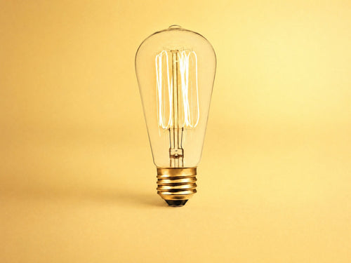 No. 1 — 60W clear glass incandescent bulb, lit, on warm yellow