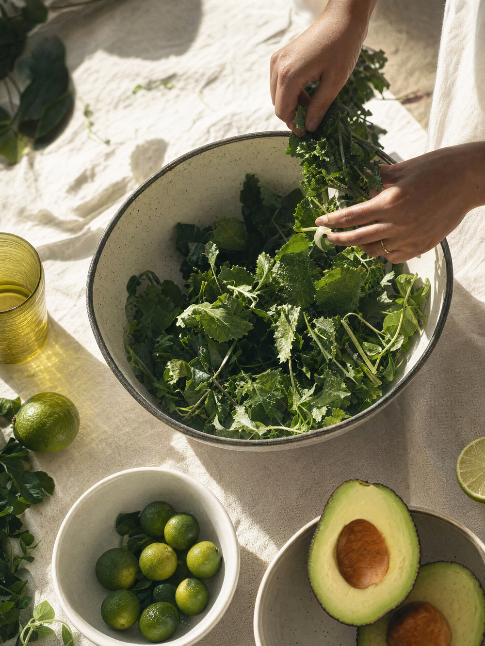 Hands tossing organic greens in a ceramic bowl