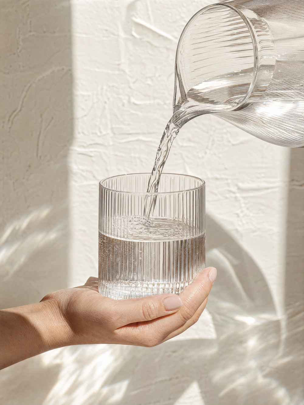 Water pouring from a carafe into a fluted glass